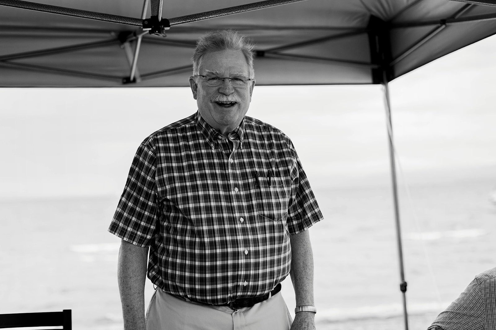 Older man smiling under a tent canopy