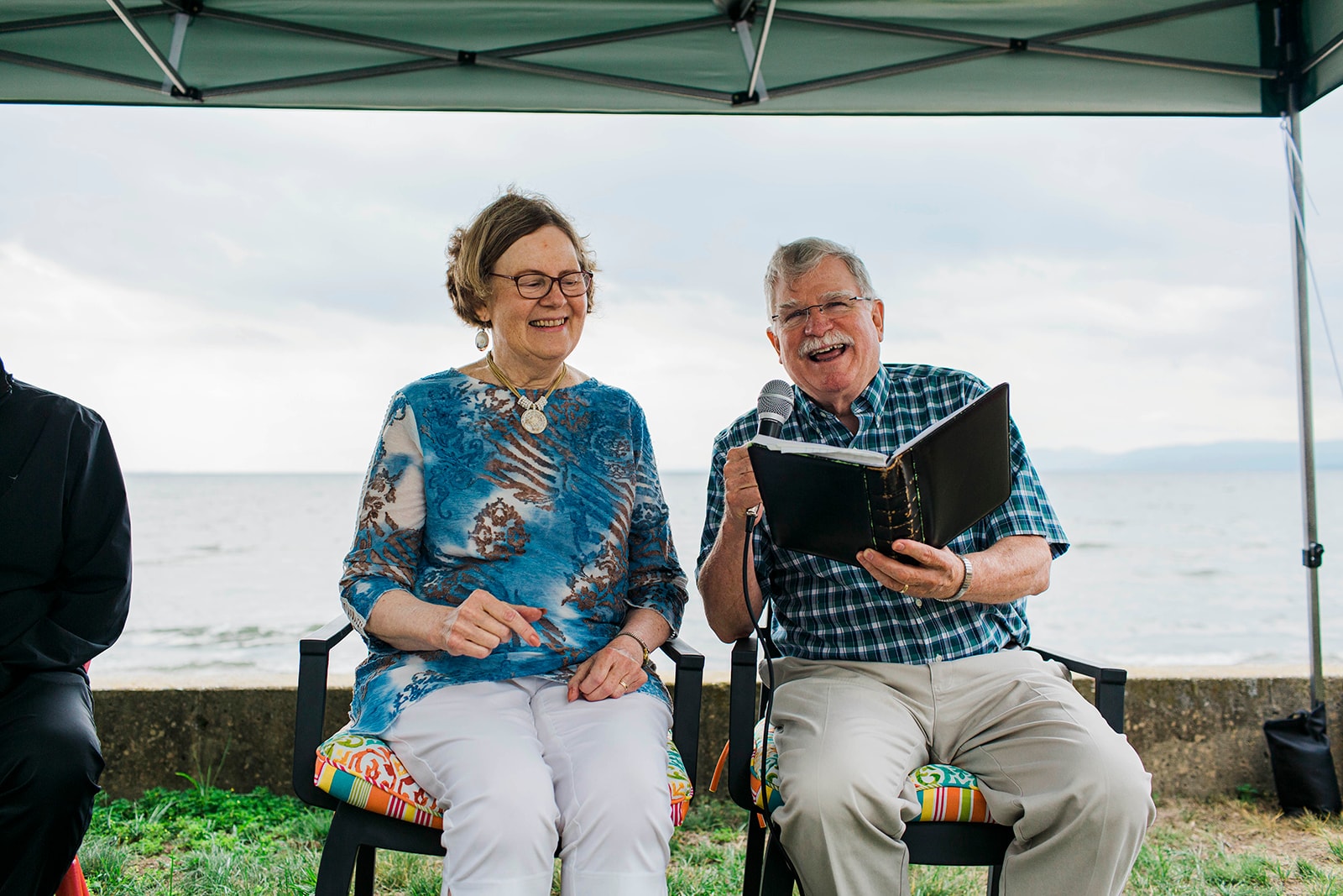 Man reading from a book next to a woman outdoors